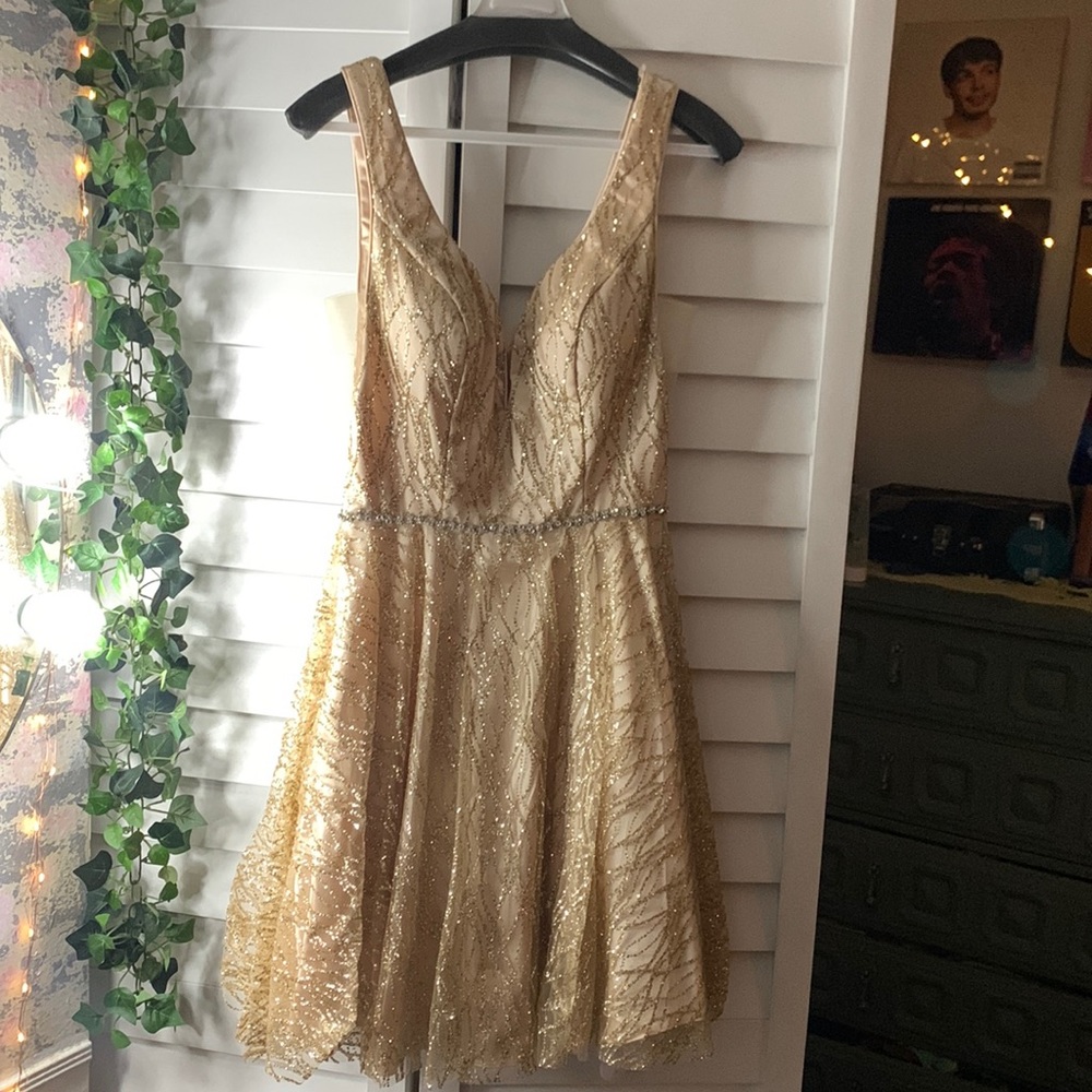 A champagne, homecoming dress with a shimmery belt and padding on the inside
